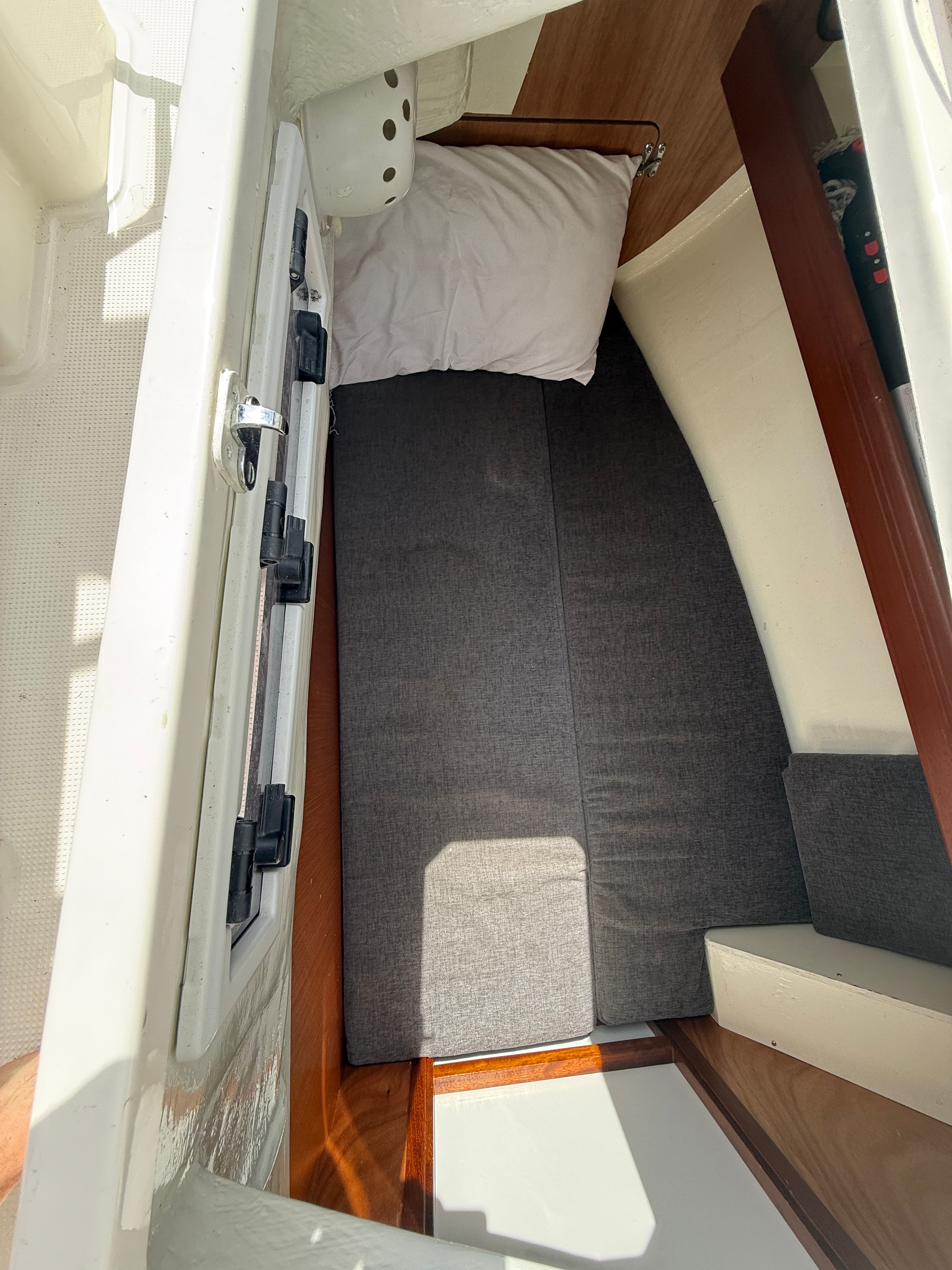 Aft cabin berth close-up — grey cushions, teak trim