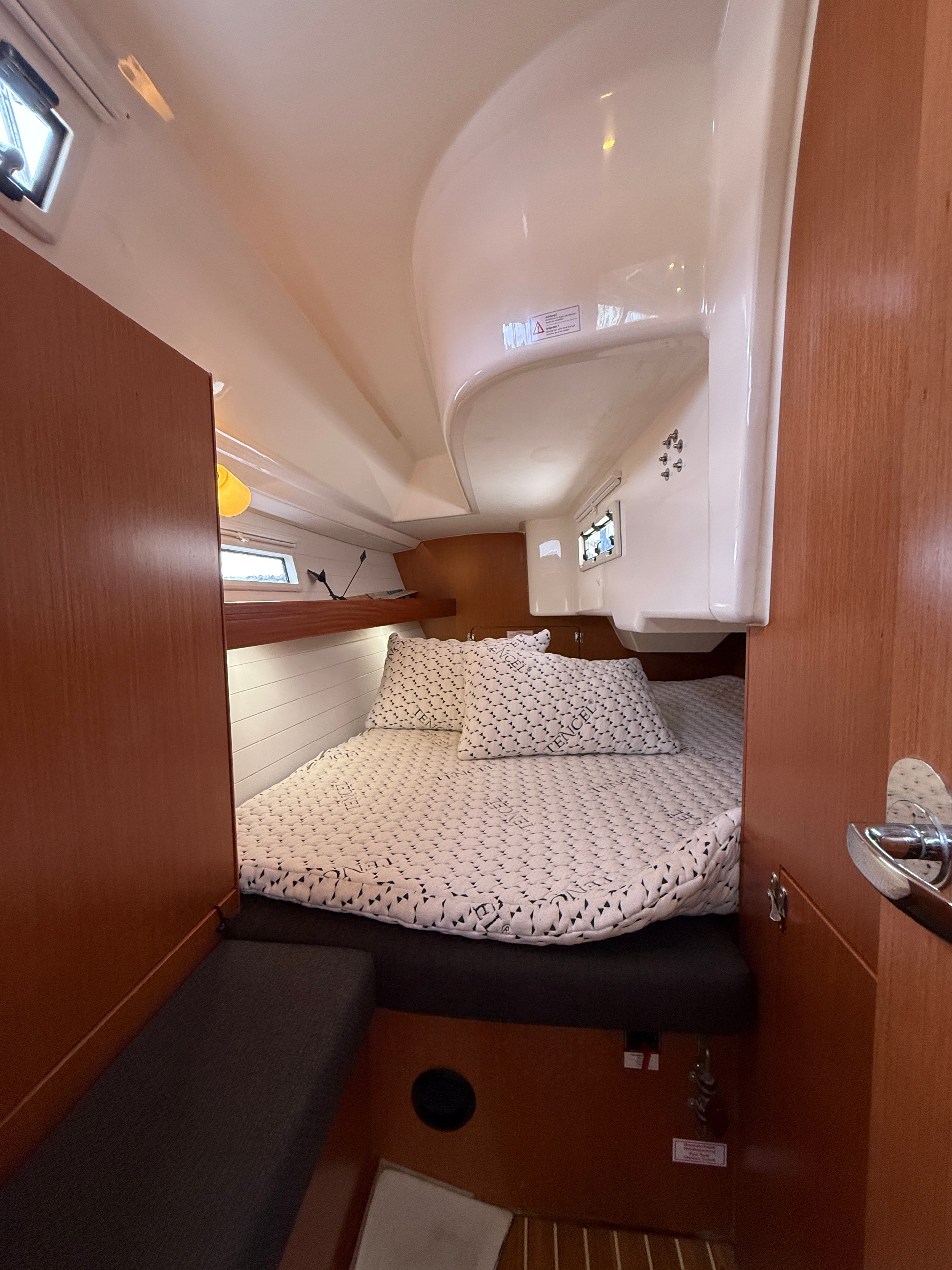 Aft double cabin — patterned bedding, teak cabinetry, portlight