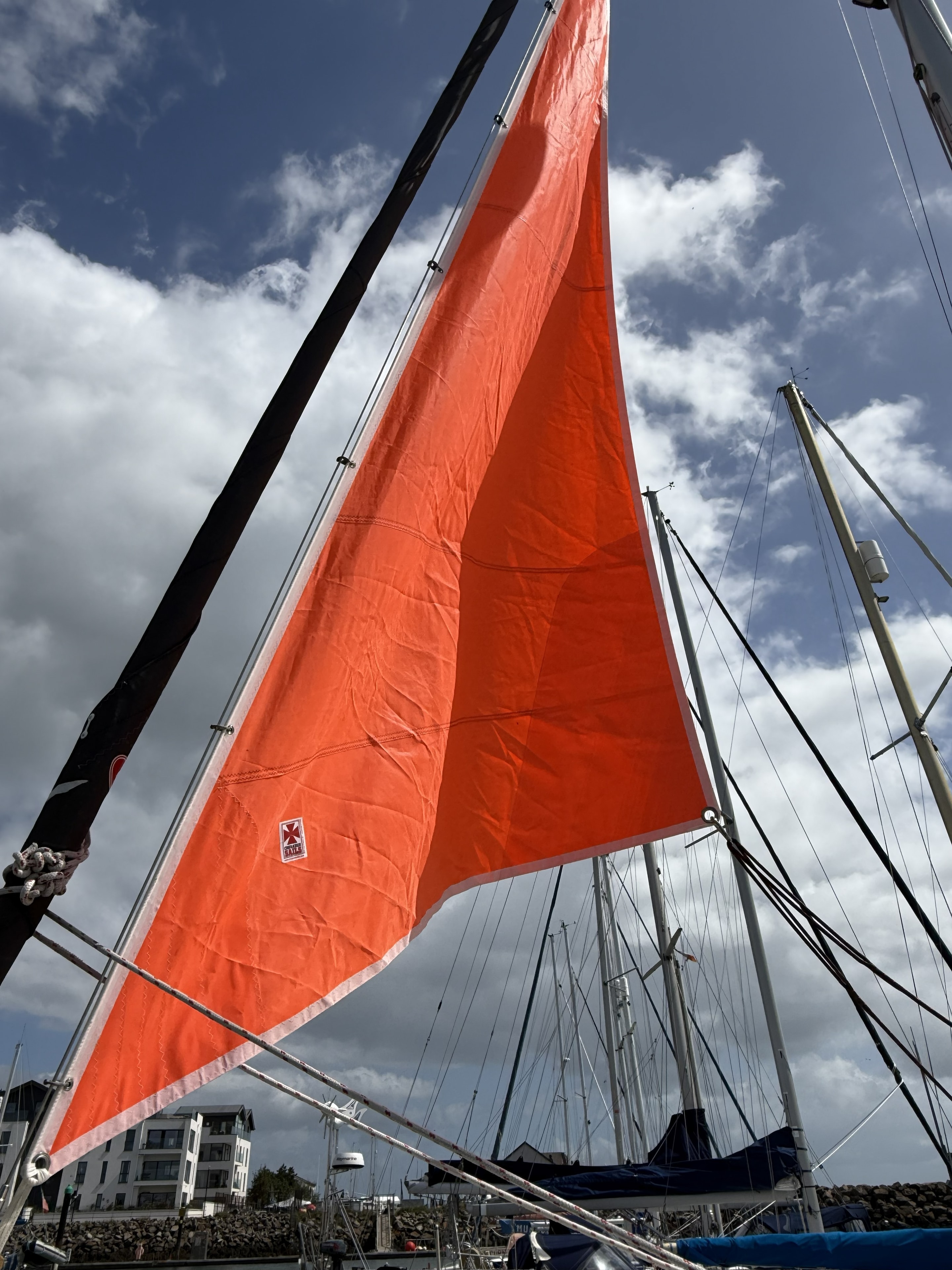 Storm jib — bright orange Crusader storm jib hoisted at marina